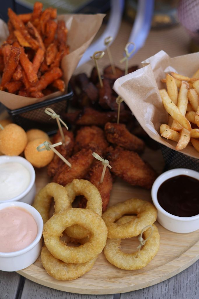 A tempting platter of onion rings, fries, and sauces perfect for indulgent snacking.